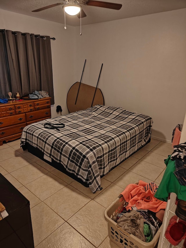 bedroom featuring a textured ceiling, ceiling fan, and light tile floors