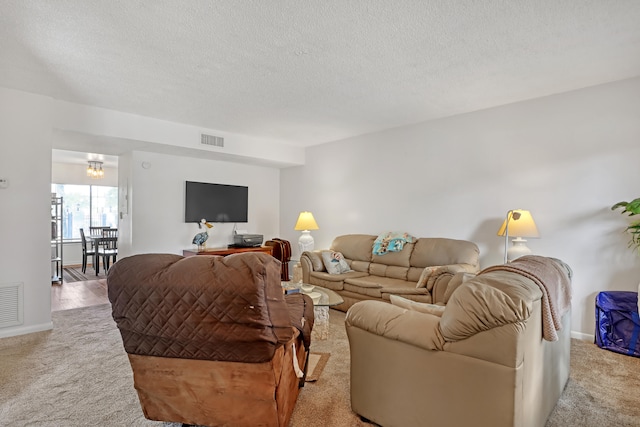 carpeted living room featuring a textured ceiling and a chandelier