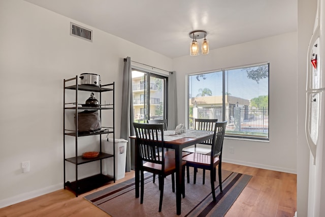 dining space with light hardwood / wood-style floors and a notable chandelier