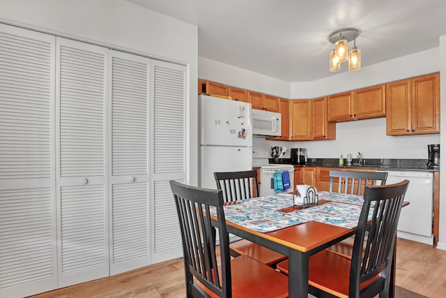 dining space featuring a notable chandelier, sink, and light wood-type flooring