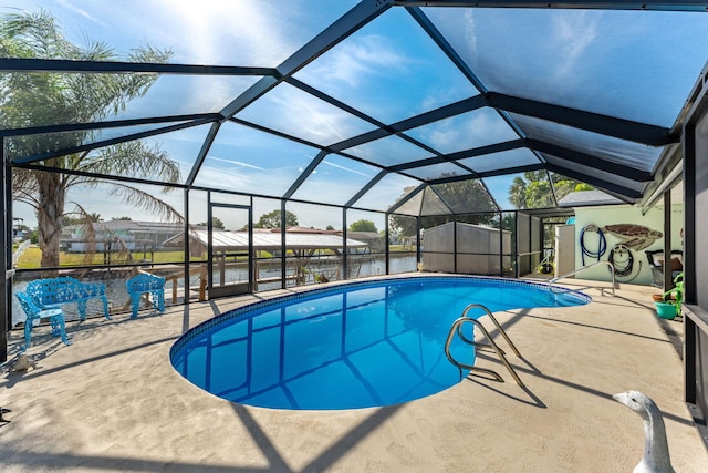 view of swimming pool with a patio, a water view, glass enclosure, and a shed