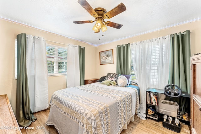 bedroom featuring ceiling fan, light wood-type flooring, and a textured ceiling