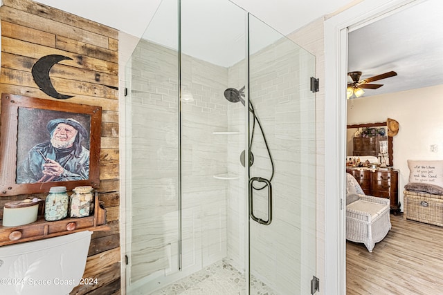 bathroom with wood-type flooring, ceiling fan, and a shower with shower door