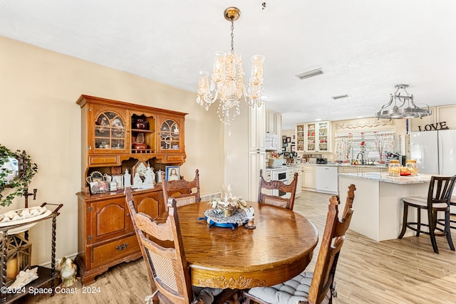 dining room with sink, light hardwood / wood-style floors, and an inviting chandelier