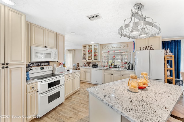 kitchen with white appliances, cream cabinets, sink, light hardwood / wood-style flooring, and a kitchen island