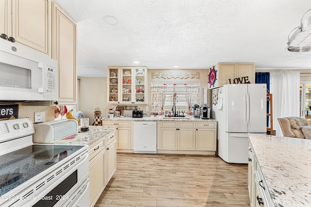 kitchen with light wood-type flooring, white appliances, a textured ceiling, and cream cabinets