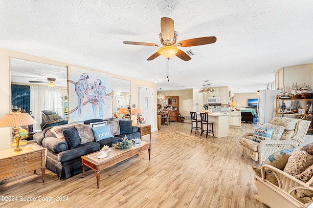 living room featuring a textured ceiling, light hardwood / wood-style floors, and ceiling fan