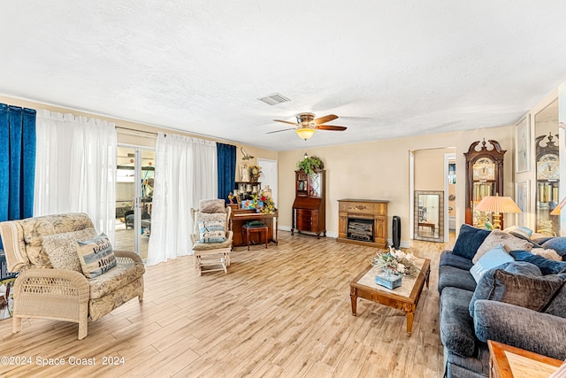 living room featuring a textured ceiling, light hardwood / wood-style flooring, and ceiling fan