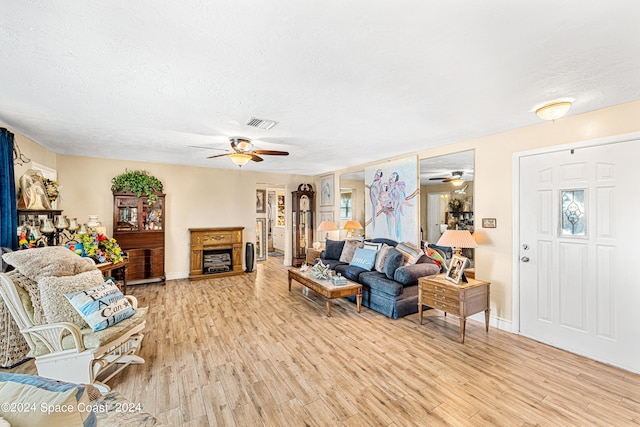 living room with a textured ceiling, light hardwood / wood-style floors, and ceiling fan