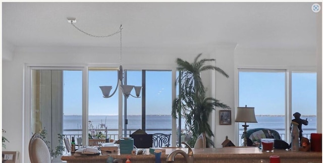 dining area with plenty of natural light, a water view, and a chandelier