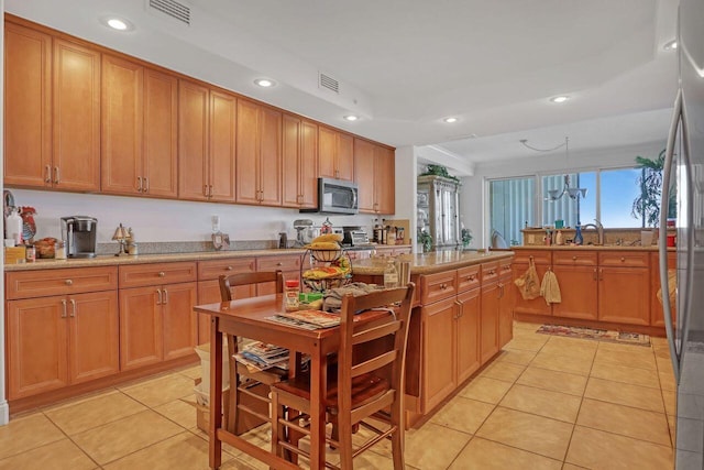 kitchen with light stone countertops, light tile flooring, and pendant lighting