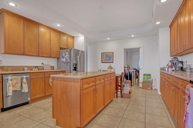 kitchen with light stone counters, a kitchen bar, light tile floors, stainless steel appliances, and a center island