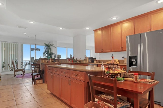 kitchen featuring stainless steel fridge with ice dispenser, hanging light fixtures, light tile flooring, and stone counters