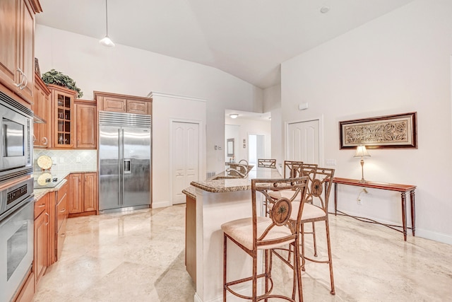 kitchen with backsplash, vaulted ceiling, stainless steel appliances, and light stone counters