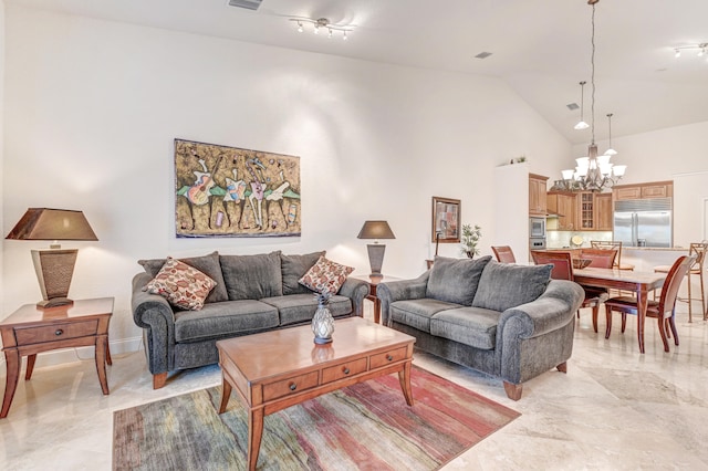 living room featuring rail lighting, a chandelier, and high vaulted ceiling