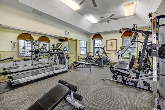 exercise room with lofted ceiling, a textured ceiling, and ceiling fan