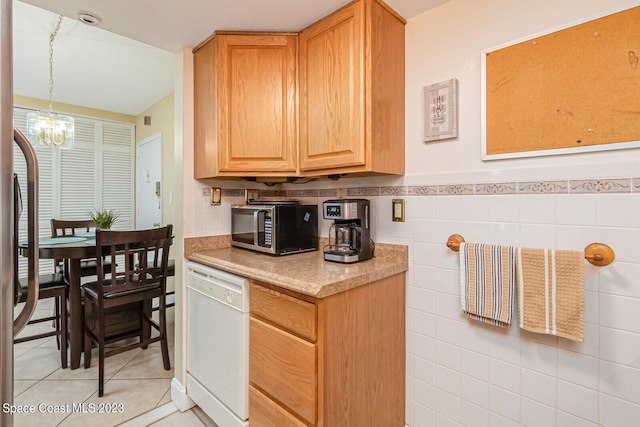 kitchen with decorative light fixtures, an inviting chandelier, dishwasher, tile walls, and light tile flooring