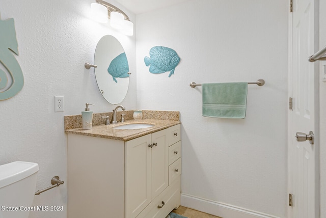 bathroom featuring toilet, vanity, and tile flooring