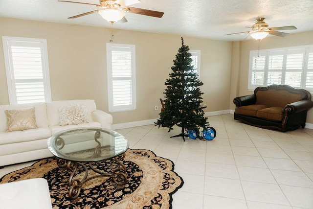 living room featuring ceiling fan, light tile floors, and a textured ceiling