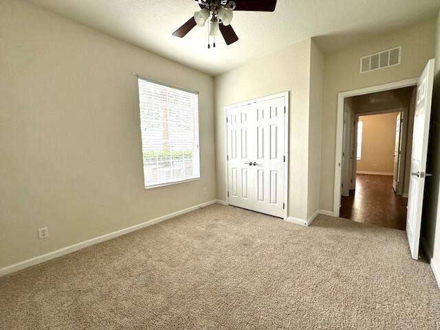 unfurnished bedroom featuring light colored carpet, a closet, and ceiling fan