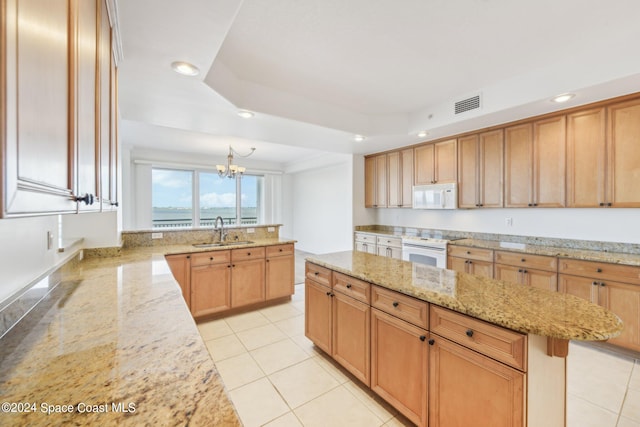 kitchen featuring white appliances, an inviting chandelier, sink, light stone countertops, and a tray ceiling