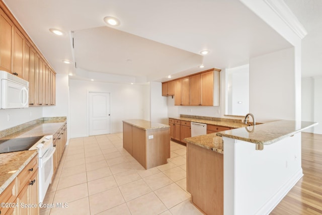 kitchen featuring light stone countertops, light tile patterned floors, a kitchen island, and white appliances