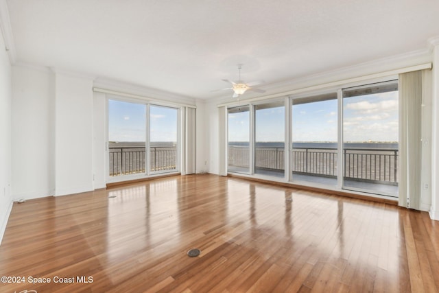 spare room featuring ceiling fan, light hardwood / wood-style floors, a water view, and crown molding