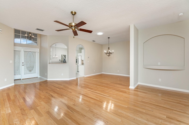 unfurnished living room featuring ceiling fan with notable chandelier, a textured ceiling, and light hardwood / wood-style floors