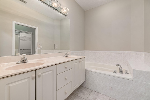 bathroom featuring tile floors, tiled tub, dual vanity, and a textured ceiling