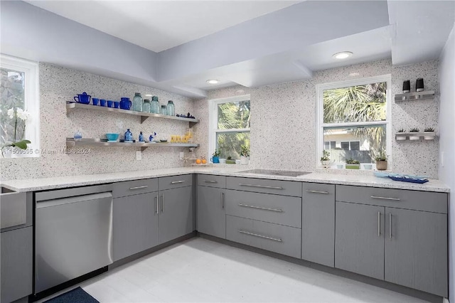 kitchen with stainless steel dishwasher, tasteful backsplash, gray cabinets, and light stone countertops