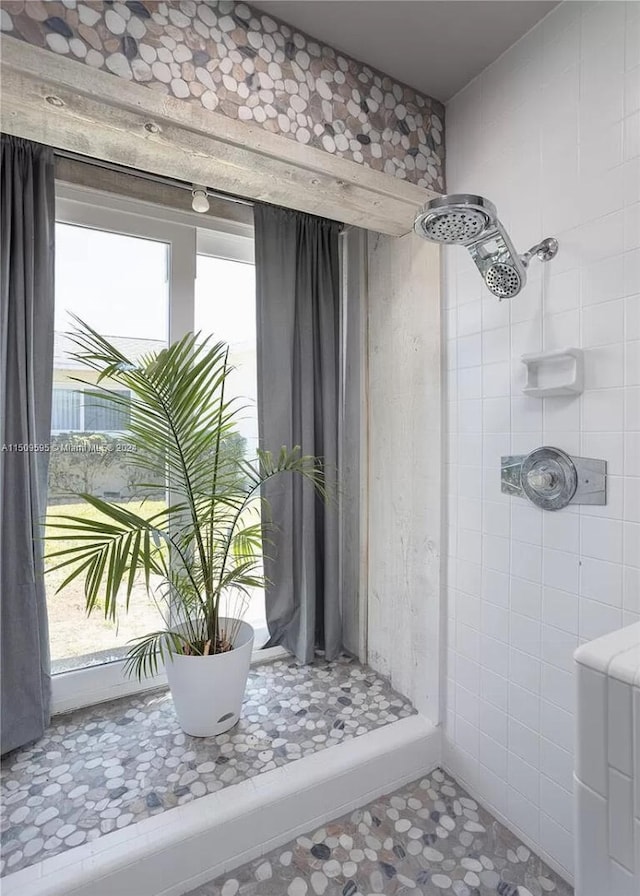 bathroom with tiled shower and tile floors