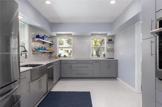 kitchen featuring backsplash, gray cabinetry, stainless steel appliances, and sink