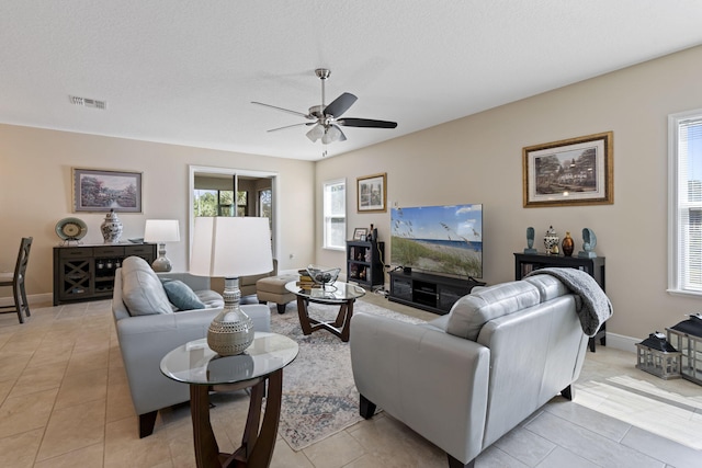 living room with ceiling fan, light tile patterned floors, and a textured ceiling