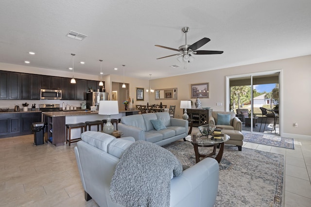 tiled living room featuring ceiling fan and a textured ceiling