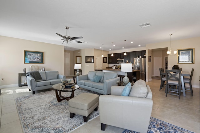 living room with ceiling fan with notable chandelier, light tile patterned flooring, and a textured ceiling