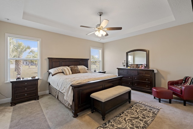 carpeted bedroom with a tray ceiling and ceiling fan