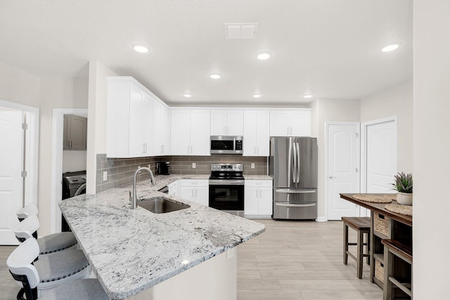 kitchen with stainless steel appliances, white cabinets, sink, and a breakfast bar area