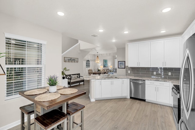 kitchen featuring white cabinets, sink, light hardwood / wood-style floors, stainless steel appliances, and light stone countertops