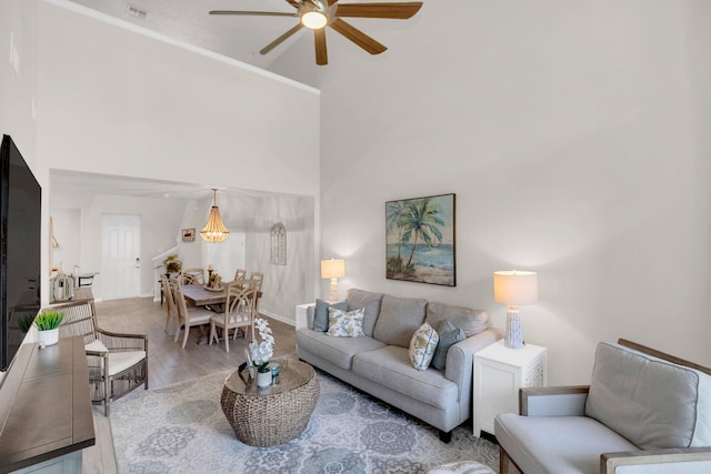 living room with light hardwood / wood-style flooring, ceiling fan, and a high ceiling