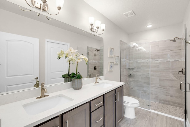 bathroom featuring wood-type flooring, a shower with door, dual vanity, toilet, and a textured ceiling