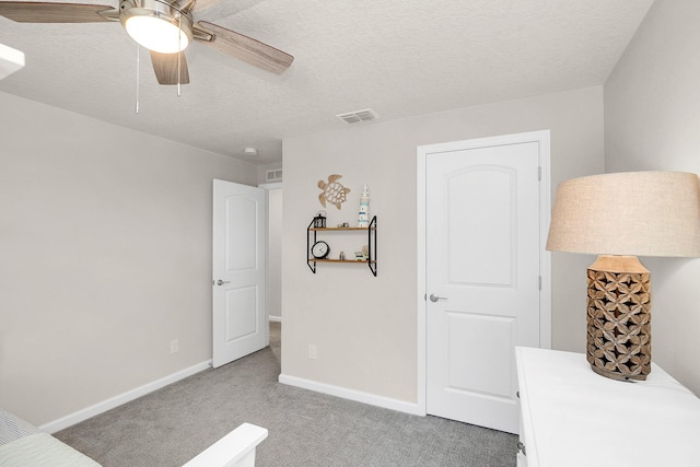 carpeted bedroom featuring ceiling fan and a textured ceiling