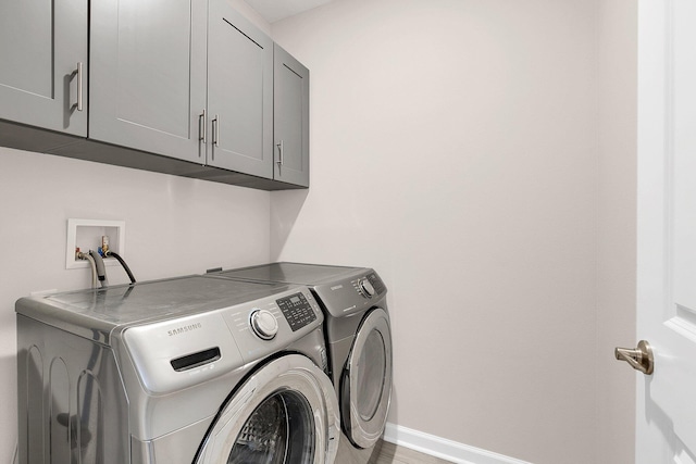 laundry area with hookup for a washing machine, washing machine and clothes dryer, and cabinets