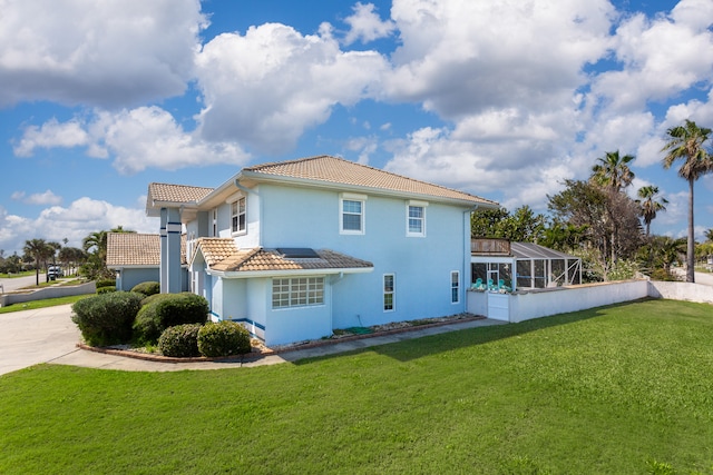 rear view of house featuring a lanai and a lawn