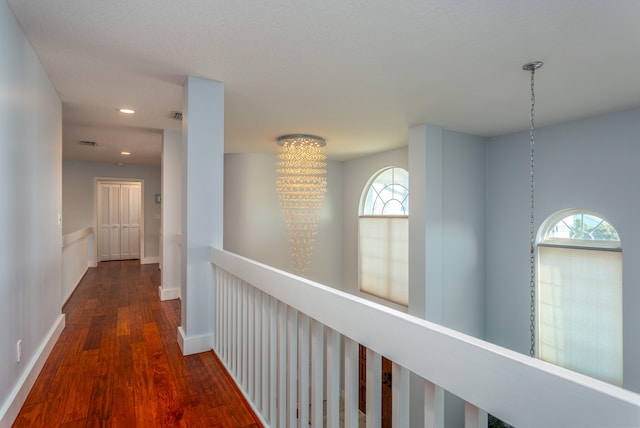 hall with dark hardwood / wood-style floors and an inviting chandelier