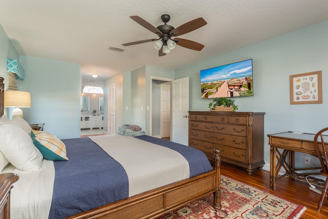 bedroom with dark hardwood / wood-style flooring, ceiling fan, and ensuite bath