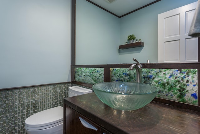 bathroom featuring vanity, crown molding, toilet, and tile walls