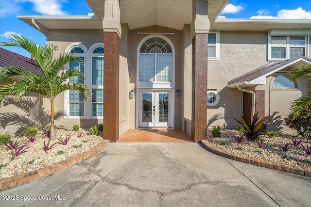 view of exterior entry featuring french doors and stucco siding