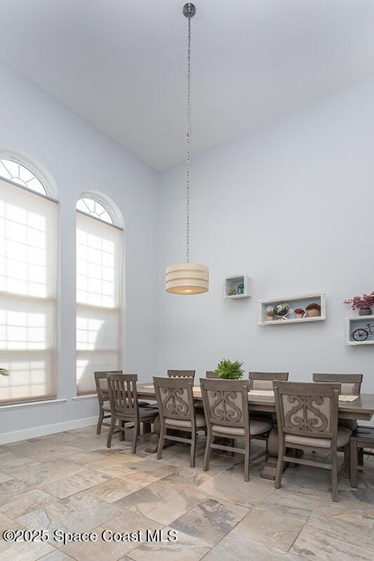 dining area featuring high vaulted ceiling and baseboards