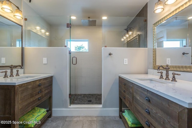 full bathroom featuring a shower stall, two vanities, and a sink