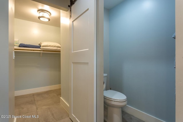 bathroom featuring tile patterned flooring, toilet, and baseboards